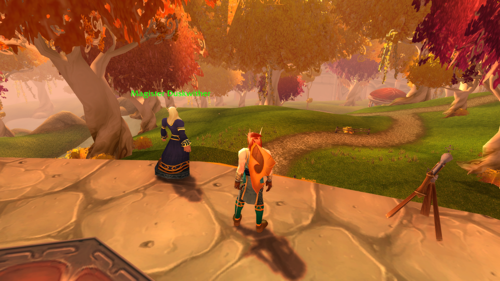 A shield-bearing blood elf stands beside Magister Duskwither overlooking a winding path through golden trees.