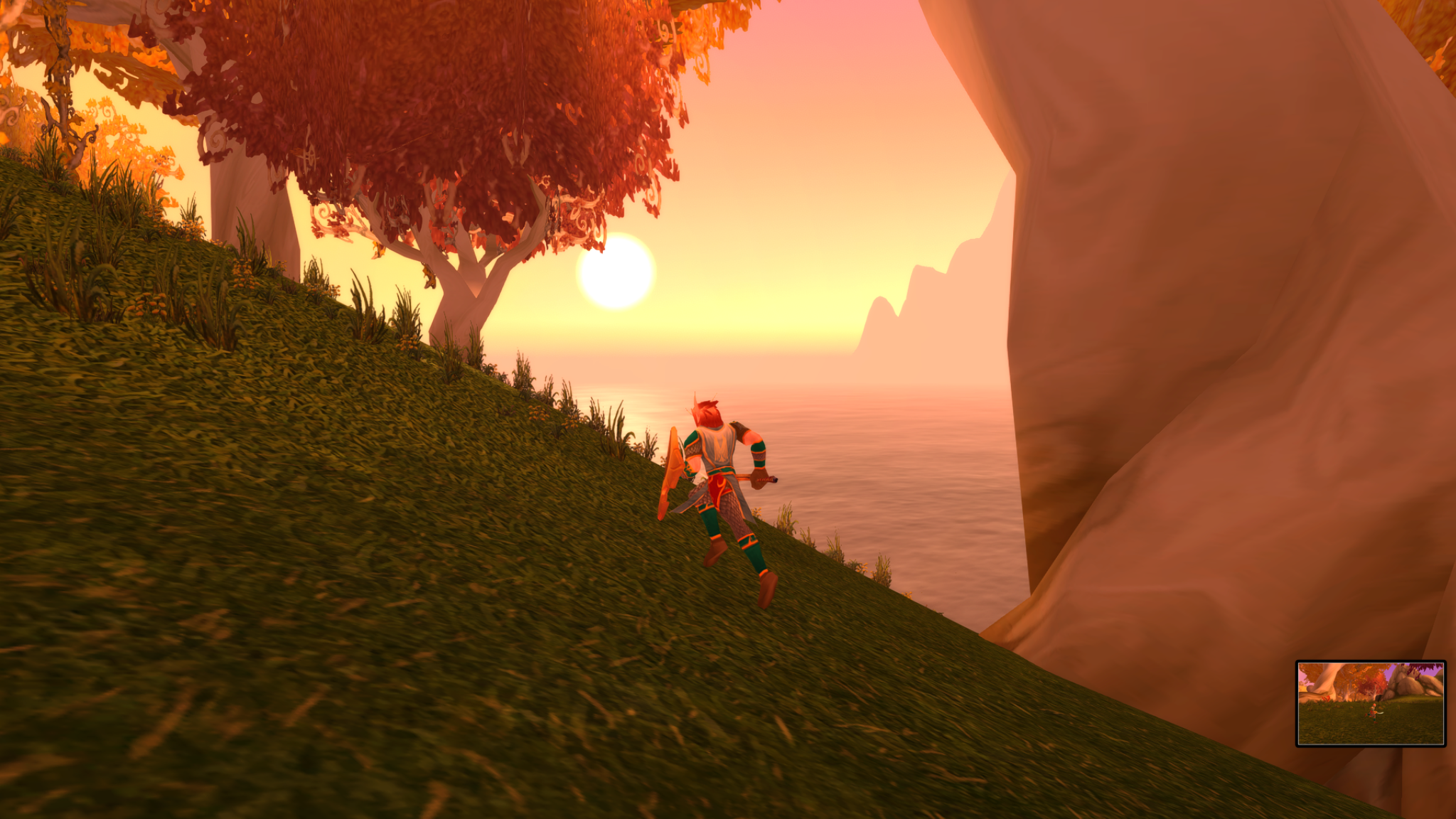 Lïr running along a grassy coastline beneath orange-leaved trees at sunset.